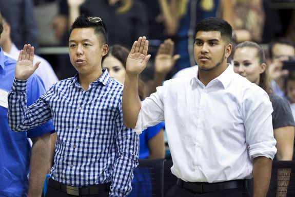 Two male students hold up their right hands