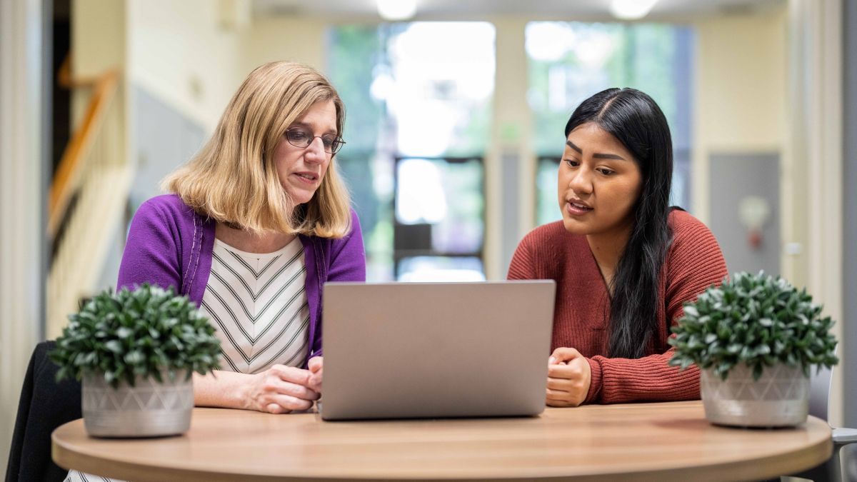 two people sitting at a table looking at a computer