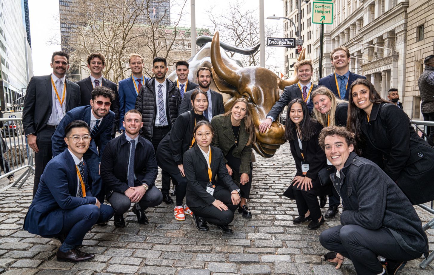 students stand next to the bull of Wall Street statue