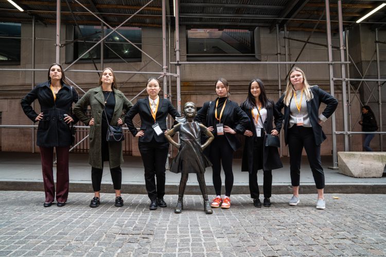 students pose with the fearless girl statue