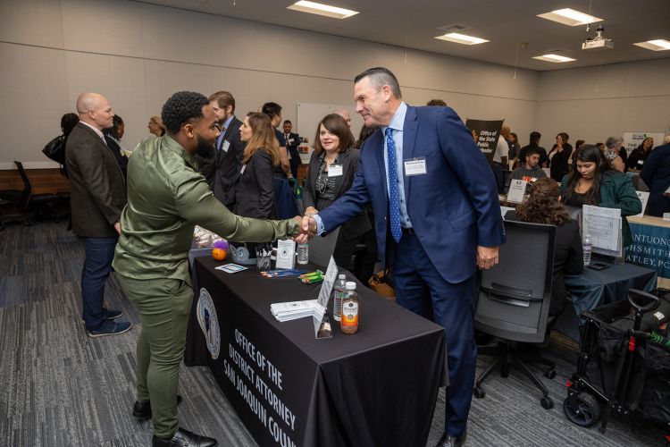A student shakes hands with a potential employer at a career fair