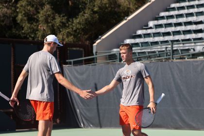 tennis players give each other a high five on the court